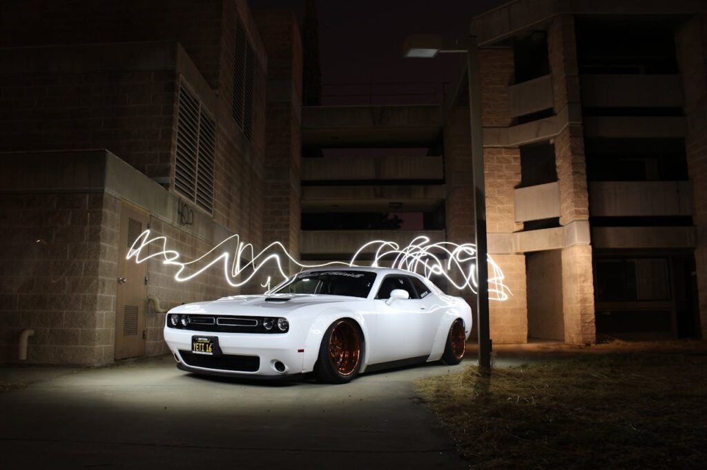 White luxury sports car parked with dynamic light trails at night against a building backdrop.