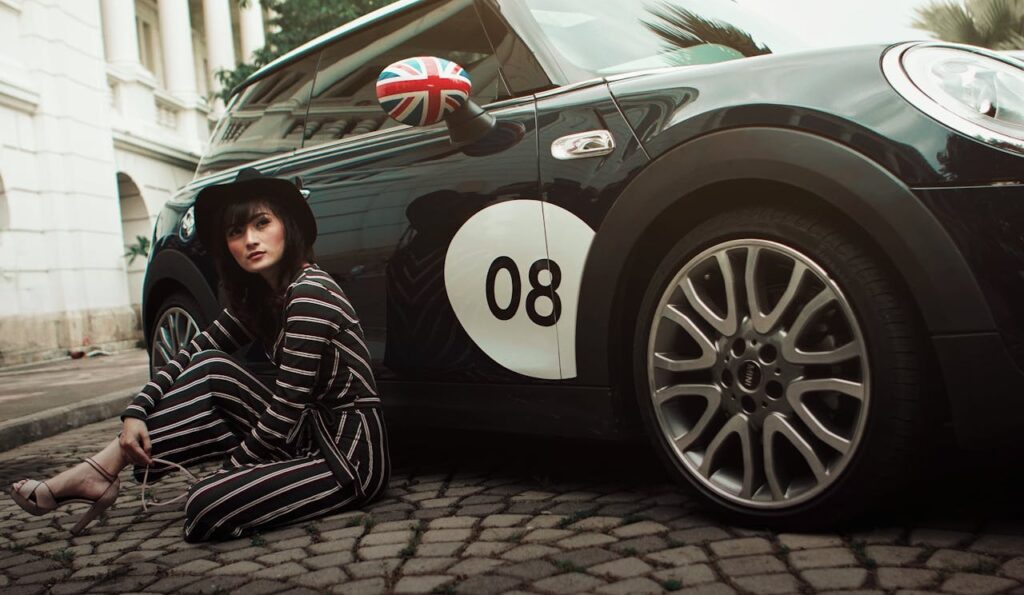 Stylish woman in striped outfit posing next to a classic Mini Cooper with Union Jack accents.